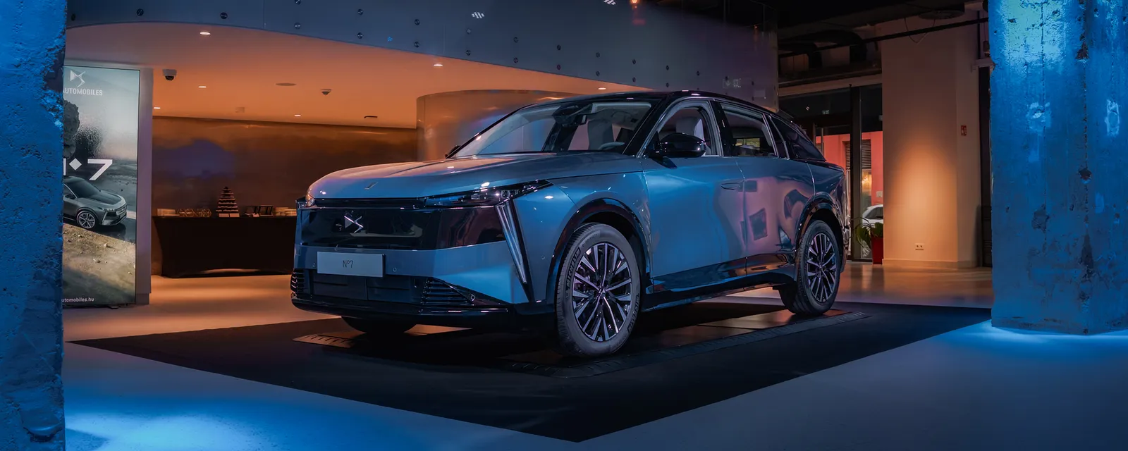 Blue SUV on display in a dark, blue-lit car launch space