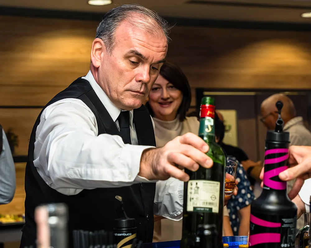 Waiter pouring drinks for guests at the bar