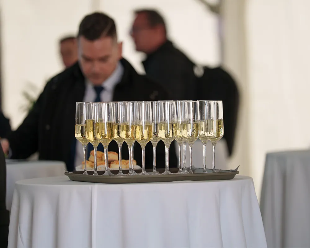 Glasses of sparkling wine on a tray, with guests behind