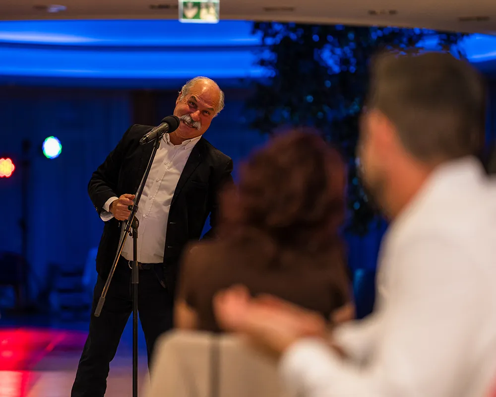 Speaker with a microphone addressing the audience in blue stage light