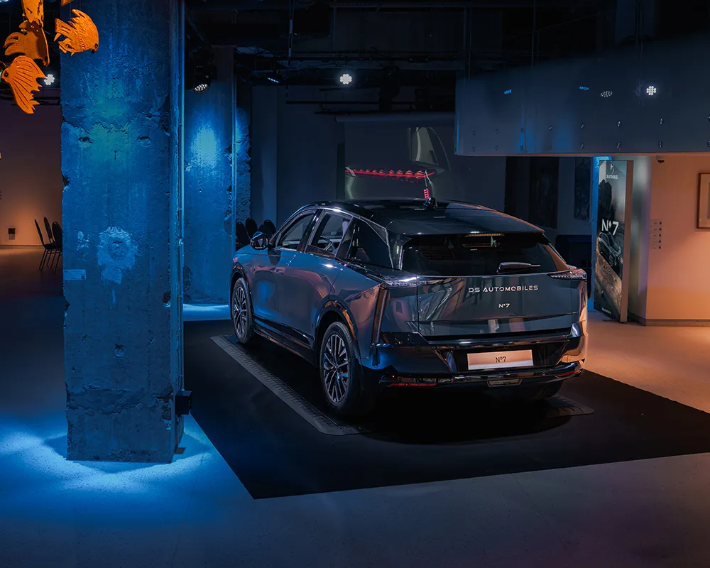 Car on display in a blue-lit venue with concrete pillars